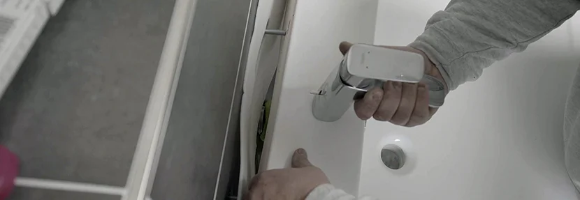 Person montiert einen Wasserhahn.